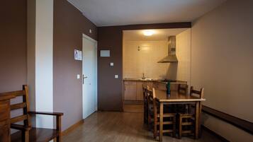 A compact kitchen with a dining area, wooden furniture, and a modern stove.