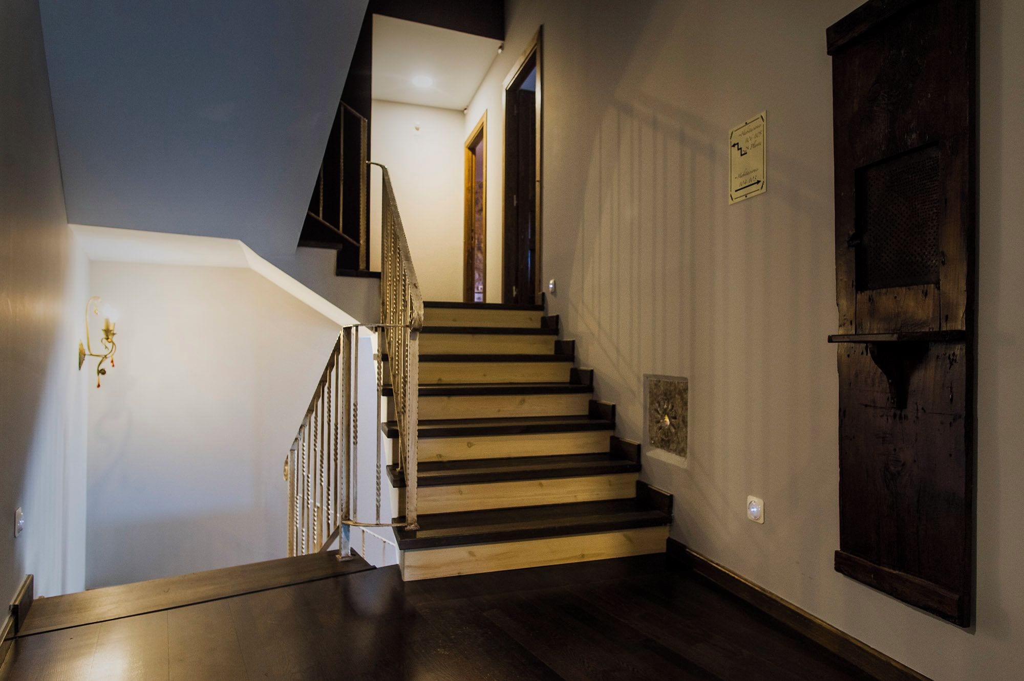 A staircase with wooden steps and a dark finish, leading to a room with a white door and a textured wall.