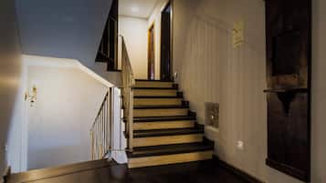 A staircase with wooden steps and a dark finish, leading to a room with a white door and a textured wall.