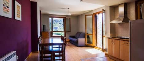 A spacious kitchen with wooden cabinets, a dining area with a table and chairs, and a view of greenery outside.