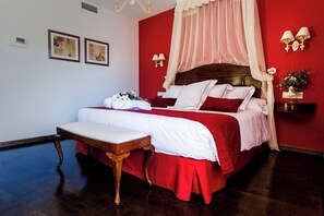 A bedroom with a large bed, a bedside table, a wooden bench, a nightstand with a lamp, and two wall-mounted light fixtures. - Ligueerre Resort (Abizanda)