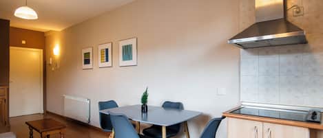 A modern kitchen with a built-in stove, a stainless steel range hood, and a dining area with a table and chairs.