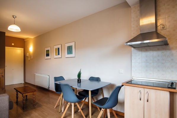 A modern kitchen with a built-in stove, a stainless steel range hood, and a dining area with a table and chairs.