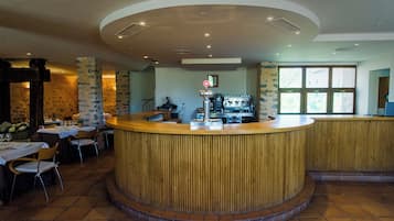 Un restaurante con barra central, mesas, sillas y una máquina de café.