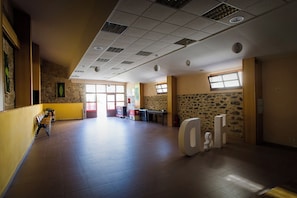 A spacious lobby with a high ceiling, stone walls, and large windows allowing natural light.