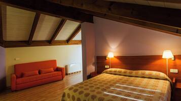 A bedroom with a wooden ceiling, a red sofa, a bed with a patterned bedspread, and two bedside lamps.