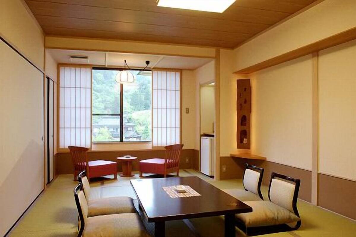 A traditional Japanese room with tatami flooring, a low table, and a view of a garden through shoji screens.
