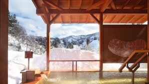 A wooden hot tub with a view of snowy mountains. - Yomogihira Onsen Izumiya (Nagaoka)
