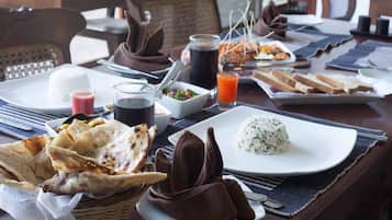 Una mesa de comedor con diversos platos, incluyendo arroz, pan plano y una ensalada.