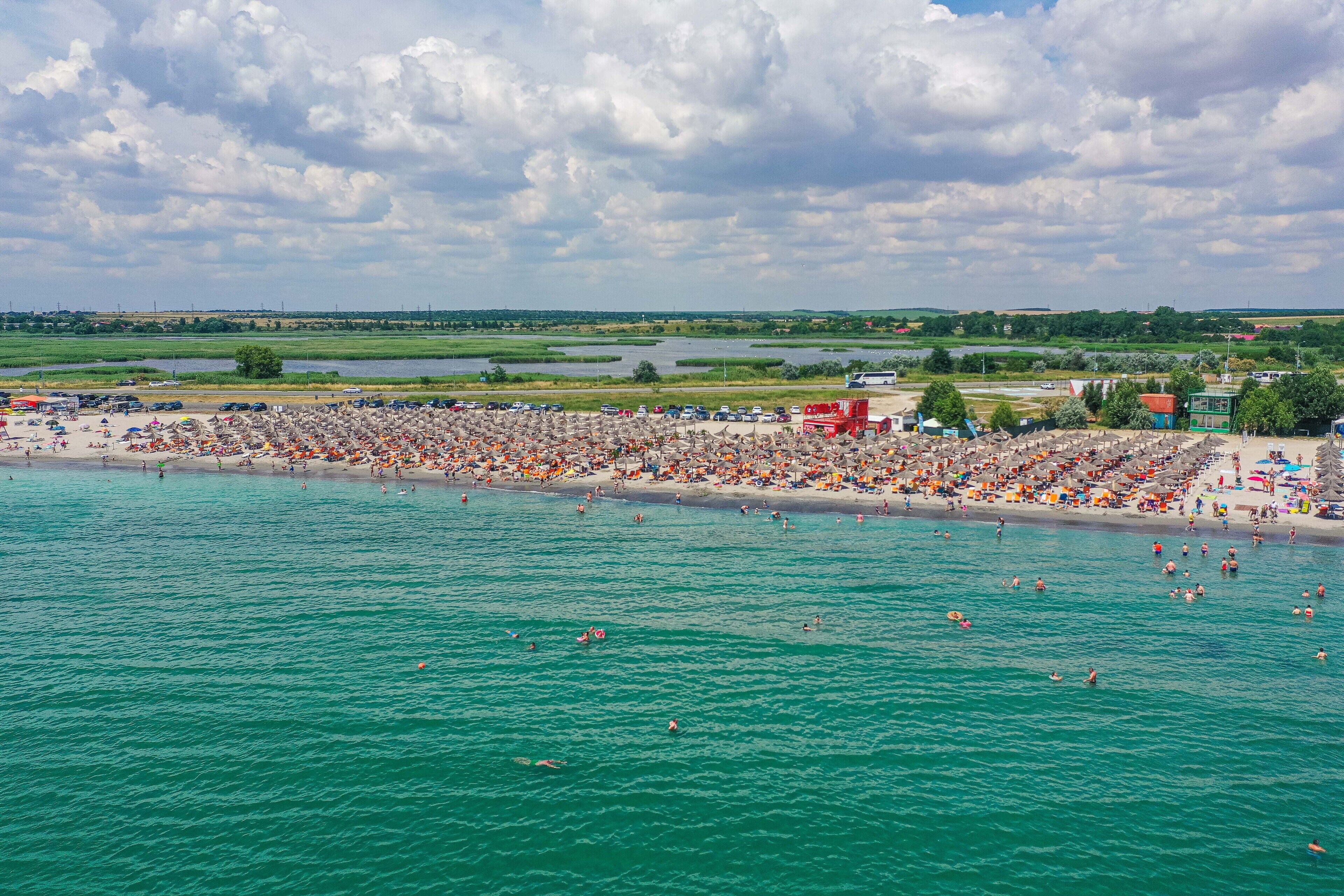 A crowded beach with people swimming and sunbathing.