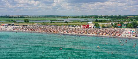 A crowded beach with people swimming and sunbathing.