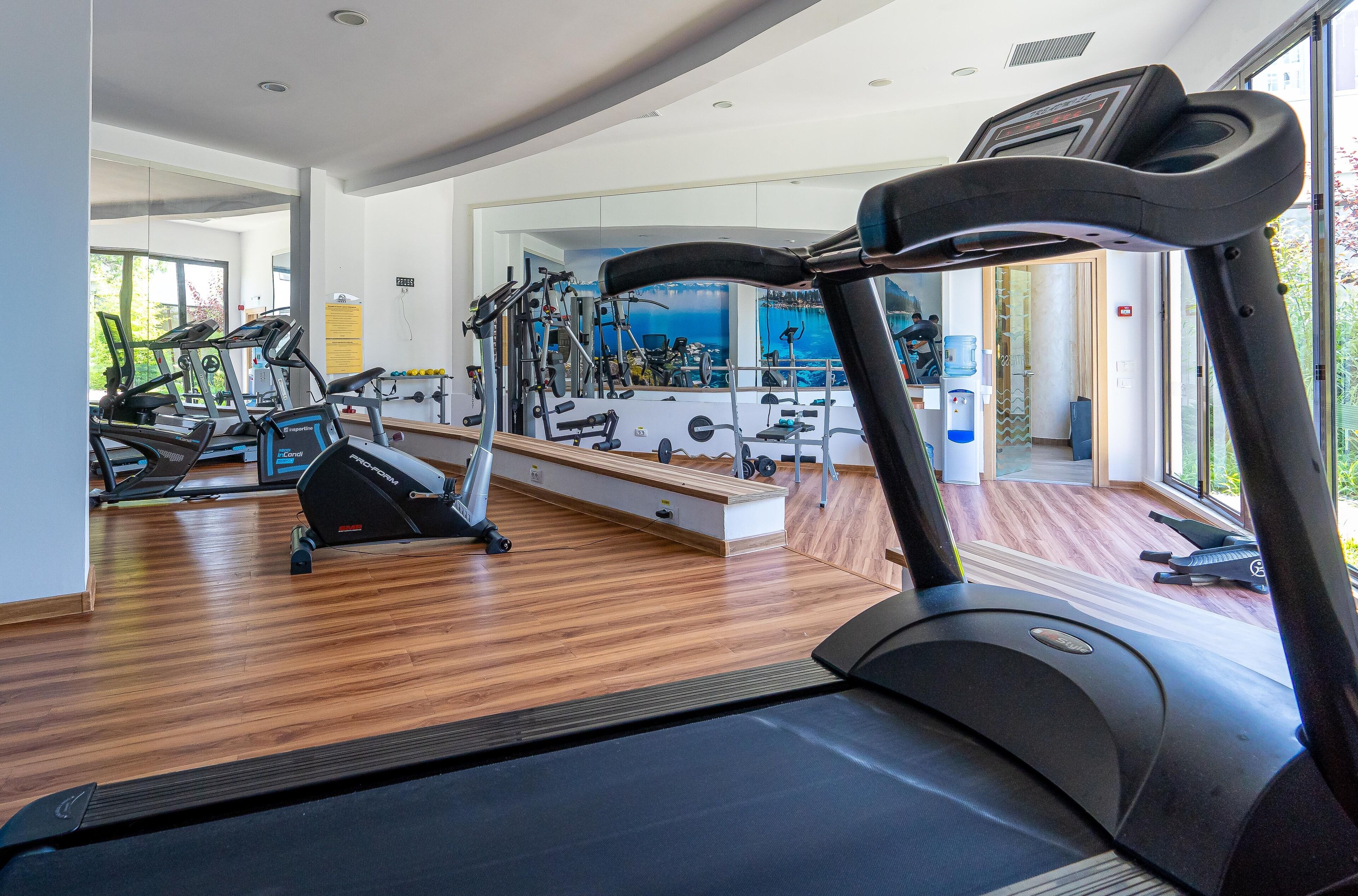 Ein modernes Fitnessstudio mit Laufbändern, Crosstrainern und Kurzhanteln.