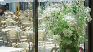En café med udendørs siddepladser og en stor blomsteropsætning i forgrunden.