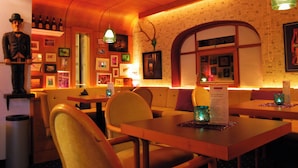 Un restaurante con mesas y sillas de madera, una estatua y cuadros en las paredes.