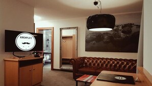 Una sala de estar moderna con un sofá de cuero, una mesa de madera, un televisor y un cuadro en la pared.