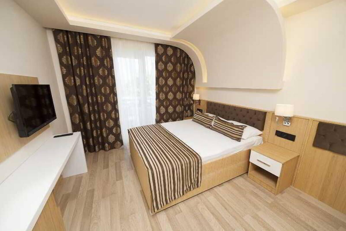 A modern hotel room with a bed, bedside table, and a TV on a stand.
