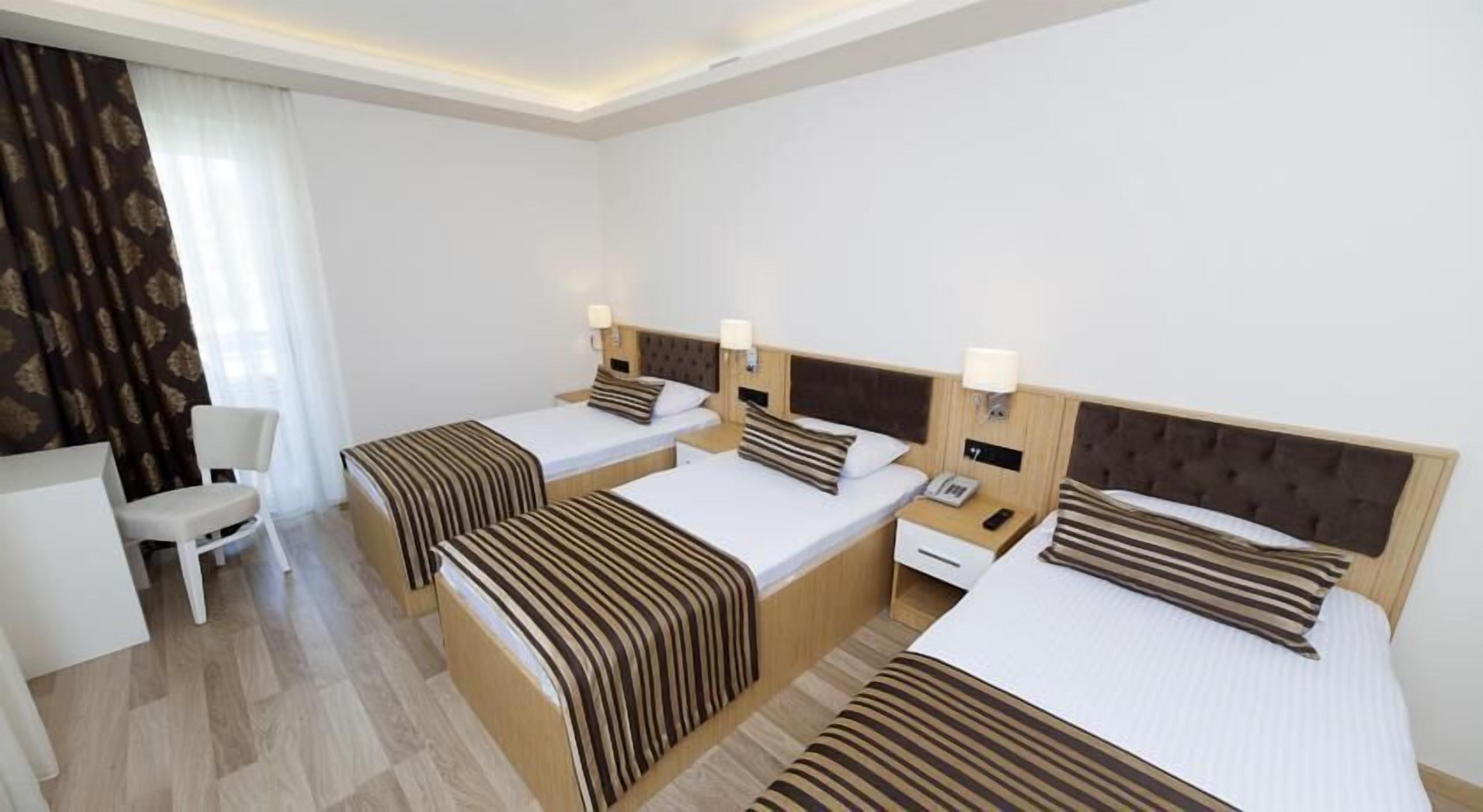 A hotel room with three beds, a desk, and a chair.