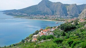 A coastal town with a prominent mountain in the background, a marina with boats, and a mix of residential buildings. - Mladen (Omis)