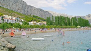 A beach with boats, people, and buildings in the background. - Mladen (Omis)