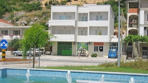 A modern building with a pool area, featuring a fountain and tiled pool. - Mladen (Omis)