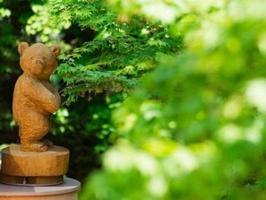 A wooden bear statue on a circular base surrounded by greenery. - Hokkaido Hotel (Obihiro)