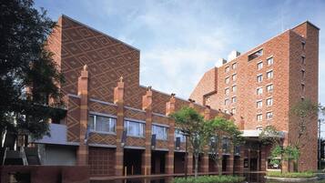 A multi-story building with a patterned facade, a courtyard with a water feature, and a clear sky.