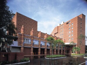 A multi-story building with a patterned facade, a courtyard with a water feature, and a clear sky. - Hokkaido Hotel (Obihiro)