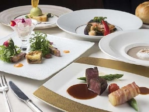 A table set with various dishes, including a salad, a soup, and a meat dish, suggesting a fine dining experience. - Hokkaido Hotel (Obihiro)