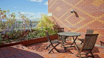 An outdoor patio with a brick wall, a table, and chairs.