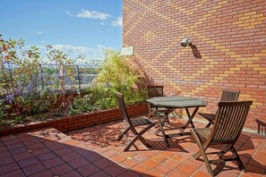 An outdoor patio with a brick wall, a table, and chairs. - Hokkaido Hotel (Obihiro)