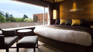 A hotel room with a large bed, a small round table, and a chair. There is a large window providing a view of the outside. - Hokkaido Hotel (Obihiro)