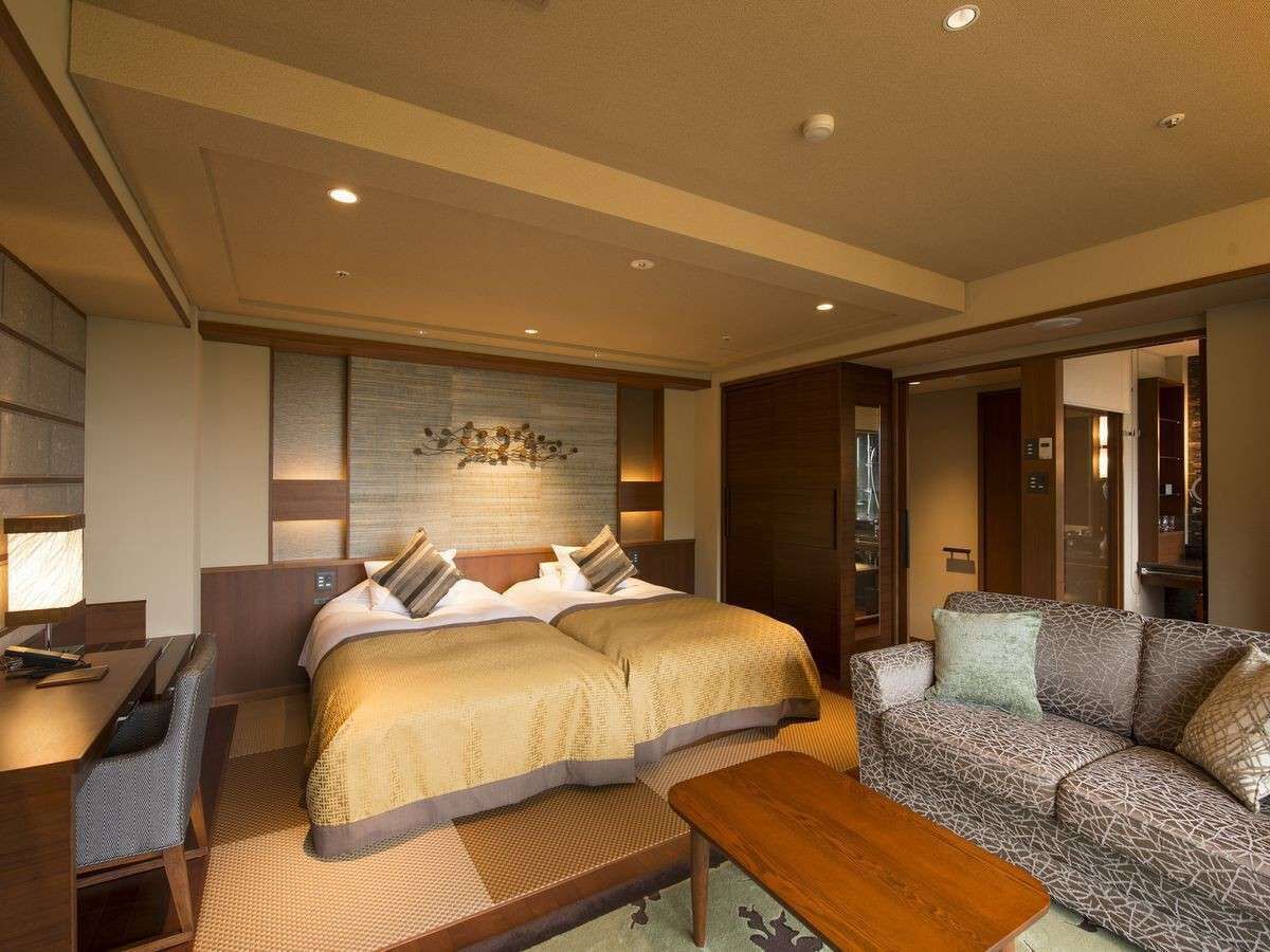 Una habitación de hotel con una cama grande, un sofá, un escritorio y una mesita.
