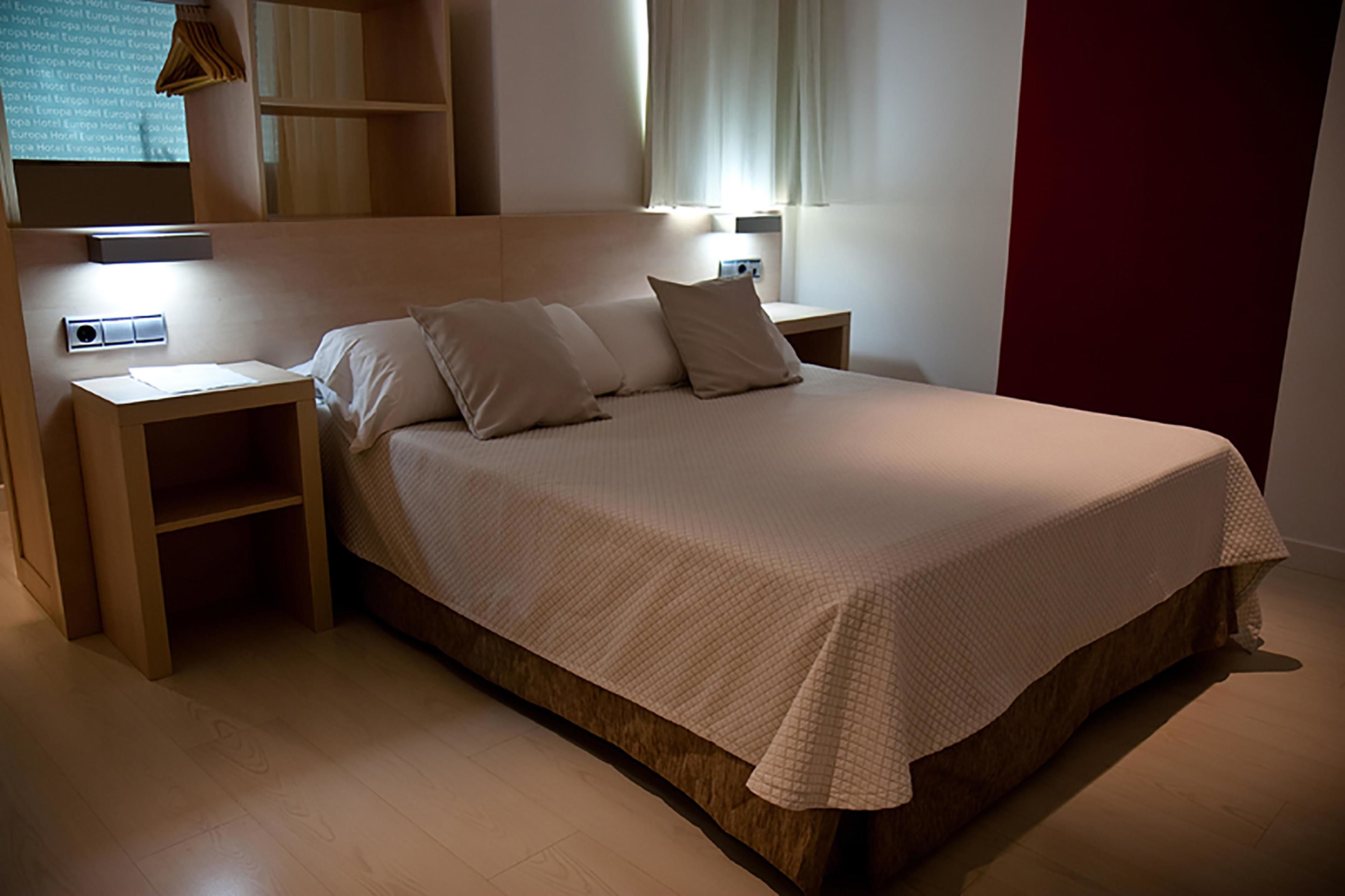 A bedroom with a bed, bedside tables, and a built-in shelf unit.
