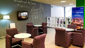 A hotel lobby with patterned chairs, a television, and a wall with a drawing and text.