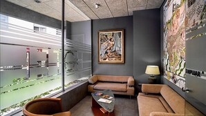 A modern office space with a large window, a sofa, a table, and a map on the wall.