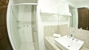 A bathroom with a glass-enclosed shower, a sink with a mirror, and a towel rack.