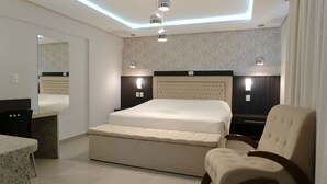 A modern bedroom with a large bed, a bedside table, a chair, and a mirror.