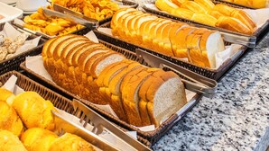 A buffet with various food items, including sliced bread, pastries, and fruits.