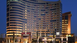 A modern hotel with a curved facade, multiple floors, and illuminated windows.