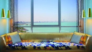 A sofa with a floral cushion facing a large window with a city view.