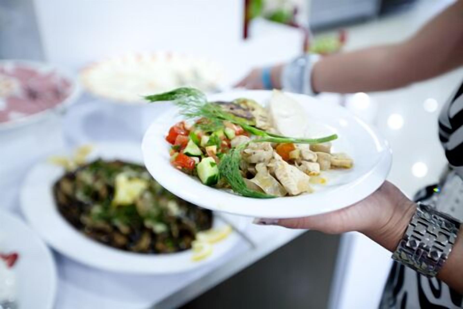 Una persona sostiene un plato con ensalada y otros platos.