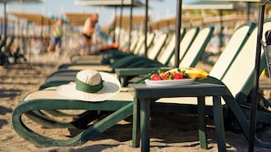 A beach with rows of green lounge chairs and umbrellas, arranged on a wooden deck. - Aleria Belport Beach Hotel - All inclusive (Kemer)