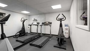 A gym with treadmills, elliptical machines, and a water dispenser.