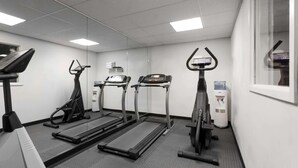 Gimnasio con cintas de correr, elípticas y dispensador de agua.