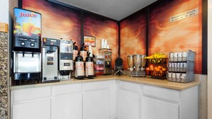 A breakfast bar with juice dispensers, coffee machines, and a fruit display.