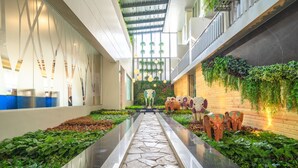 Un atrium moderne avec un chemin en pierre, des plantes vertes et des vases décoratifs.