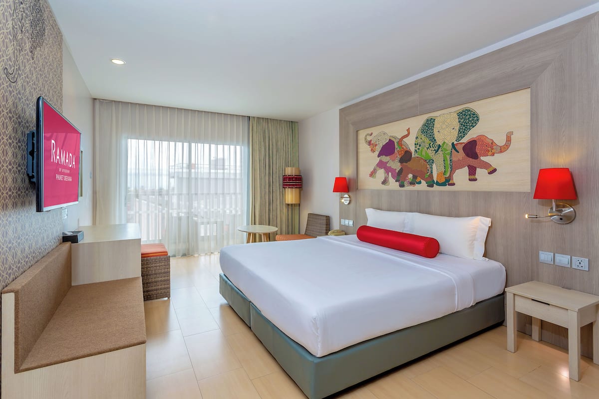 Hotelkamer met een groot bed, een bureau, een stoel, een televisie en een kunstwerk aan de muur.