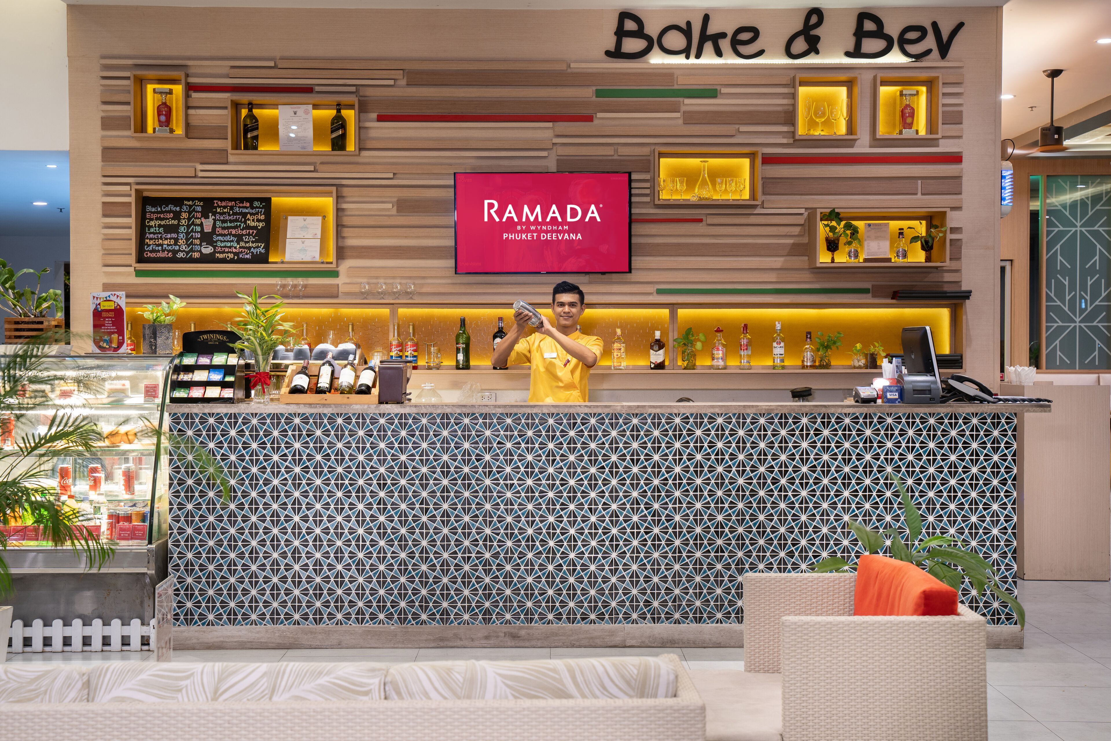 A bar area with a counter, a menu board, and a TV screen displaying "RAMADA".