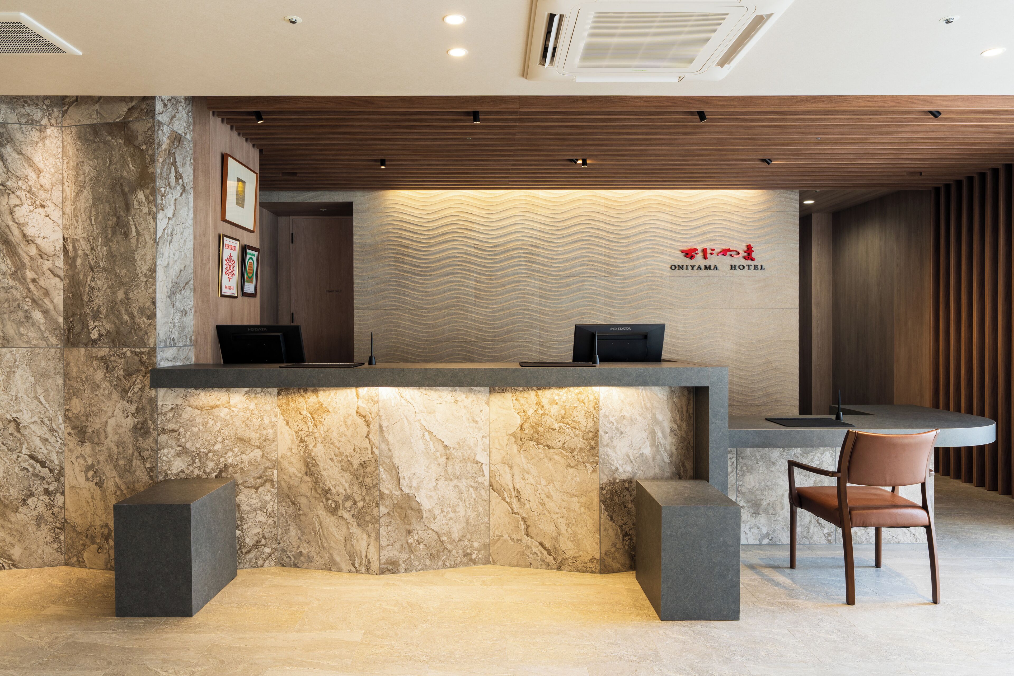 A reception desk with a marble wall, wooden paneling, and a sign for the Omiya Hotel.