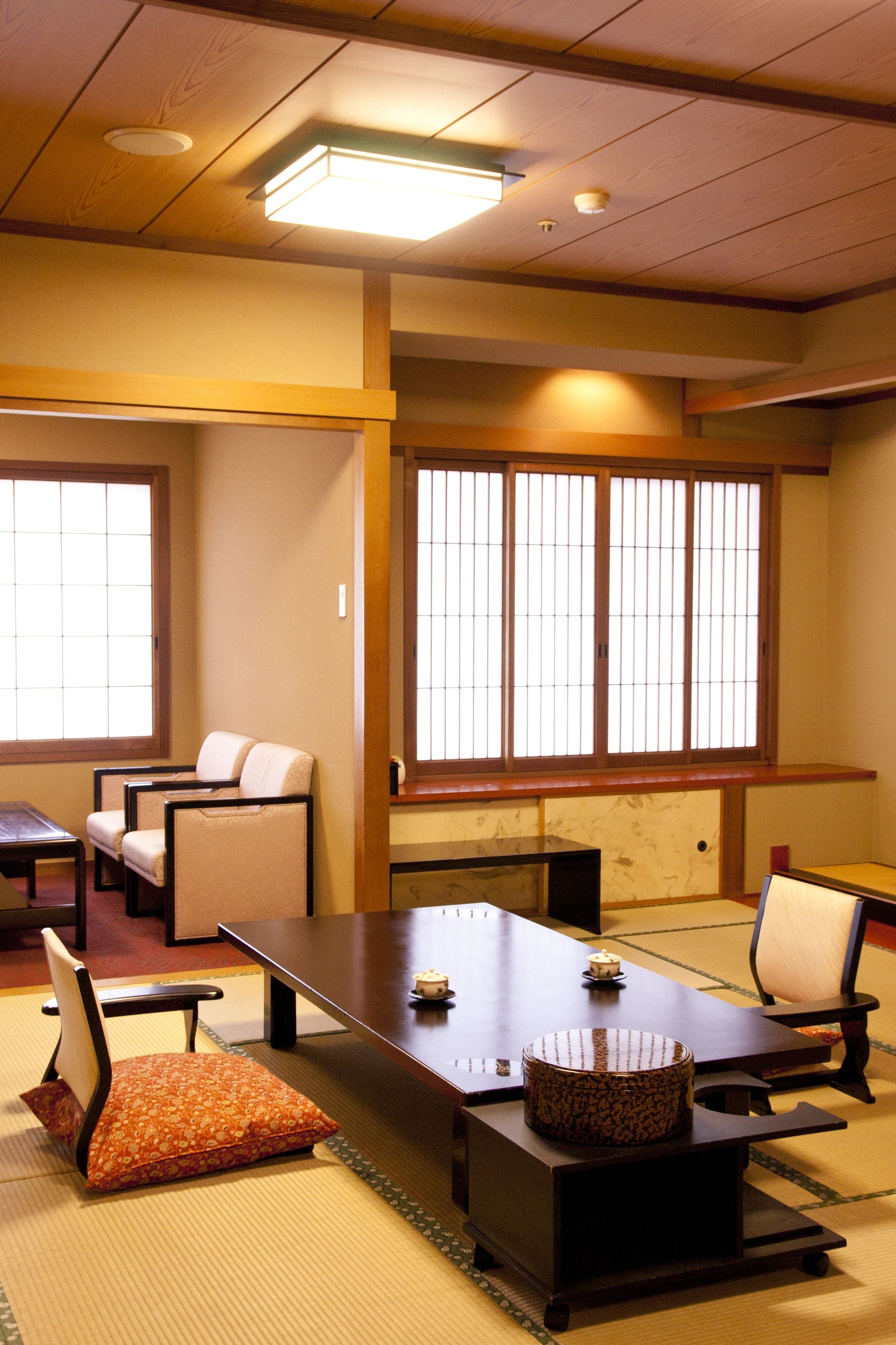 Um quarto japonês tradicional com tatames, uma mesa baixa e um sofá.